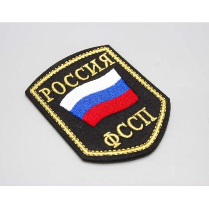 Где купить Шеврон вышитый РОССИЯ ФССП,черное поле нить (металл золотистый цвет) в Москве недорого с доставкой по России
